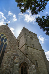 Fototapeta na wymiar Presteigne church window, tower and yew tree in Powys, Wales. With a blue sky background