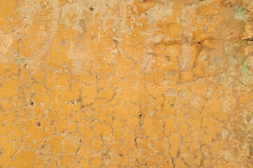 The texture of old cracked yellow paint on a concrete wall