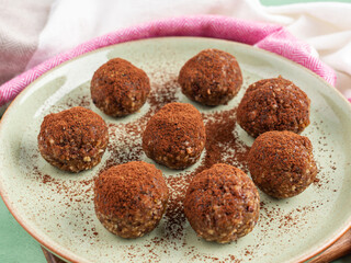 Chocolate cocoa energy balls with nut butter on green dish