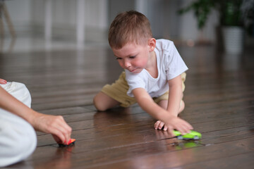 Expressive baby boy playing with a toy car with mother.
