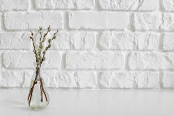 Vase with willow branches on brick background