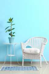 Stylish armchair and table with houseplant near color wall