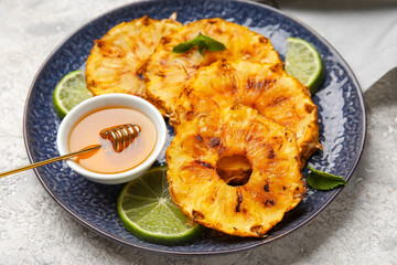 Plate with grilled pineapple slices, honey and lime on grunge background, closeup