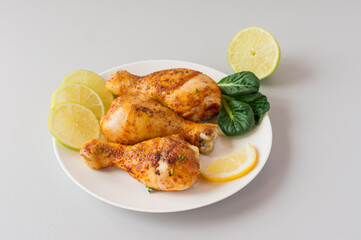 Grilled chicken drumsticks and vegetables on white table