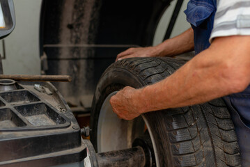 Car mechanic balancing car wheel on a computer machine balancer in auto repair service.