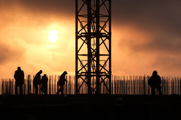 Industrial landscape against the background of a disturbing sky, silhouette of metal structures of a house construction site