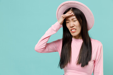Naklejka premium Depleted exhausted emaciated knackered sad young brunette asian woman 20s with hand on forehead wear pink clothes hat isolated on pastel blue color background studio portrait. People emotions concept