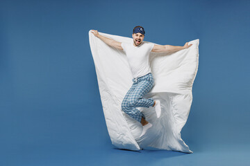Full length side view funny young man 20s wearing pajamas jam sleep mask resting relaxing at home...
