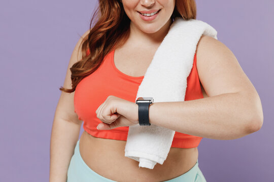 Close up cropped photo shot young overweight plus size big fat fit woman in red top towel warm up training look at smart watch isolated on purple background home gym Workout sport motivation concept