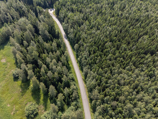 View of gravel road through pine and fir, coniferous forest. Aerial, drone photography taken from...