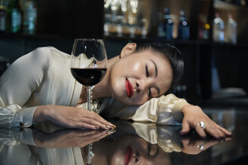 Elegant woman fell asleep at bar in restaurant after drinking couple glasses of red wine
