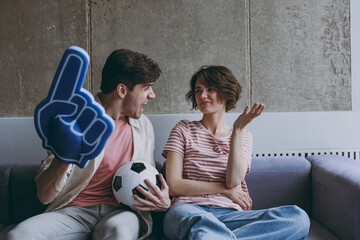 Displeased indignant sad couple friends woman man football fans in casual clothes foam glove finger...