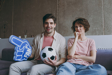 Surprised friends couple sad woman man football fans in casual clothes foam glove finger up support...
