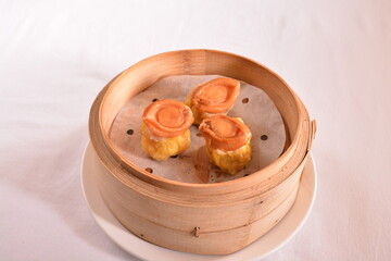 Hong Kong steamed siew mai meatball dumpling with wanton skin abalone and roe in bamboo basket asian dim sum menu