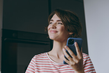 Young fun wistful housewife woman in casual clothes striped t-shirt use mobile cell phone chatting...