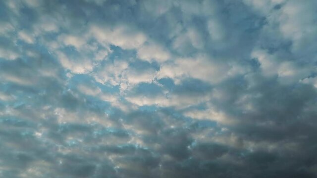 Time lapse. Clouds of unusual shape fly across the blue sunset sky. The autumn evening is coming fast and it will be dark soon.
