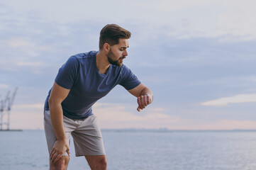 Young strong sporty fit sportsman man wear sports clothes warm up training leaning on knees take...