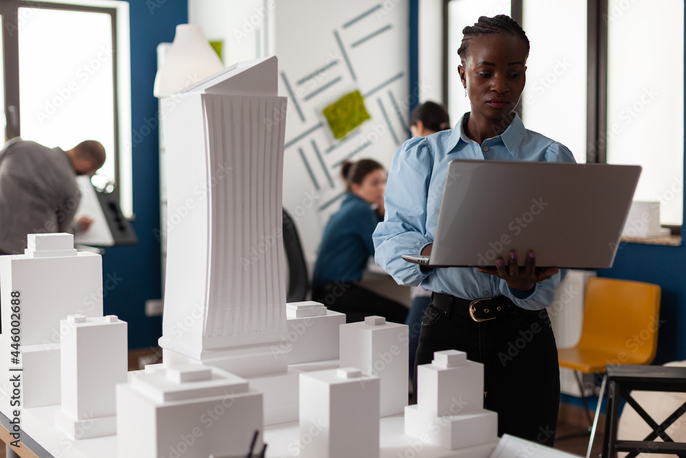 Aufkleber african american architect at business workplace looking at laptop and blueprint plan for building m