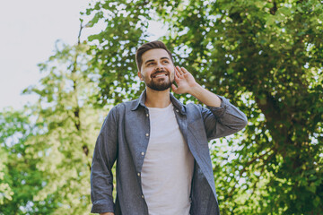Bottom view young happy man in blue casual shirt walk try to hear chirping birds rest relax in...