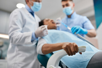 Close-up of woman holding tight to a chair during dental procedure.