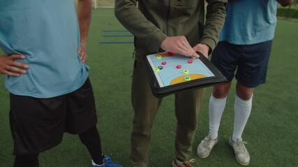 Soccer young coach explaining match tactics to group of diverse multiracial soccer players in sportswear on football pitch at daybreak, giving personal instructions to each sportsman outdoors - Powered by Adobe