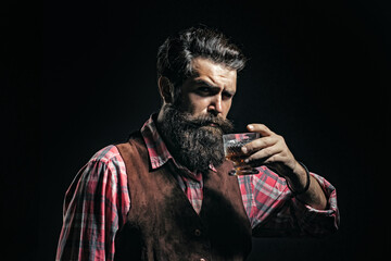 Luxury alcohol drink. Elegant and stylish man in classical wear holding glass with wiskey in hand. Cheerful bearded man is drinking expensive whisky.