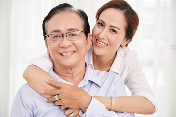 Portrait of smiling happy senior husband and wife embracing and looking at camera