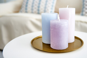 A closeup shot of purple and blue candles on the white table as a room decoration