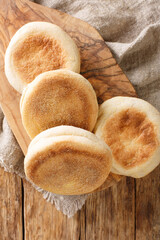 Homemade English muffins buns close-up in a board on the table. vertical top view from above