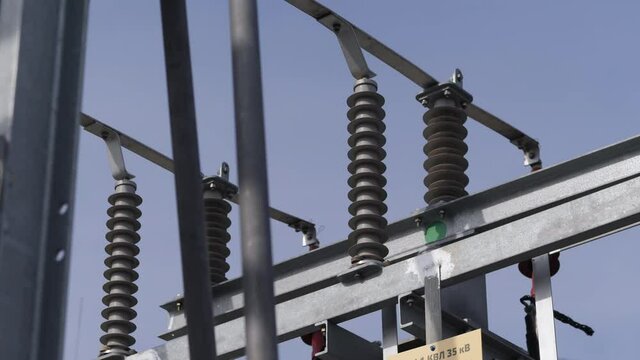 Metal support with insulators on electricity production substation switchyard under blue sky close low angle shot