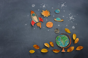 Back to school concept. Top view banner of globe with autumn dry leaves over classroom blackboard background
