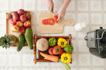Housewife slicing tomato at kitchen table when cooking delicious dish for family dinner, view from the tp