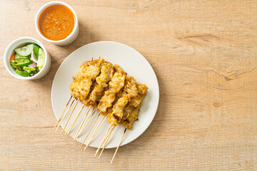 Pork satay with peanut sauce pickles which are cucumber slices and onions in vinegar