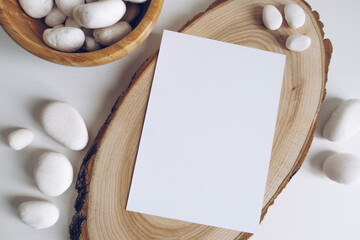 Boho vertical postcard mockup with white pebble and wooden cut section on white table background. Rustic bohemian image. Space for text. Good for handicrafts banners. Copyspace mock up