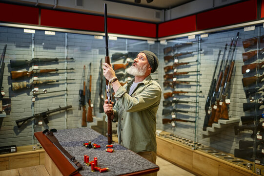 Bearded hunter buying hunting rifle in gun store