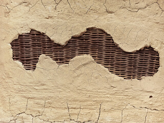 Picture Cracked wall with fallen plaster revealing rattan. African dwellings