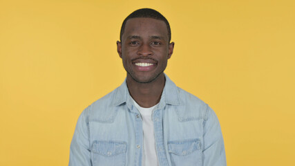Young African Man Smiling at Camera, Yellow Background 