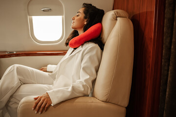 Rest on the plane. A young girl in a white business suit is napping while sitting by the porthole...