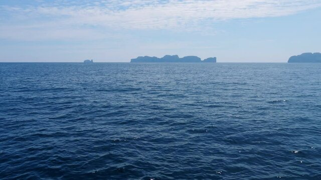 Phi Phi Islands silhouettes seen ahead, from ferry boat. Camera slightly turn left, looking to Koh PhiPhi Leh. Beautiful blue sea water seen down and around. Sunny and hot weather at Thailand