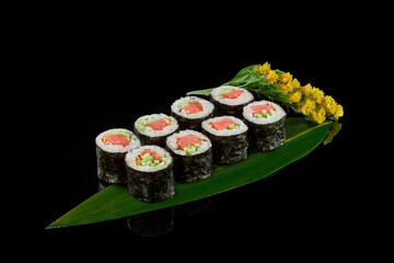 Maki sushi rolls with smoked salmon and cucumbers on bamboo leaf