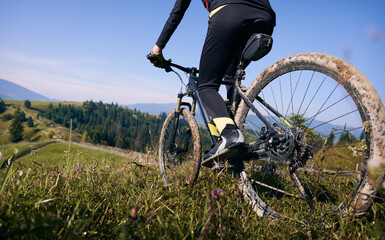 Close up, low angle view on a bike with cyclist. Man's legs riding his bicycle on grass in summer...