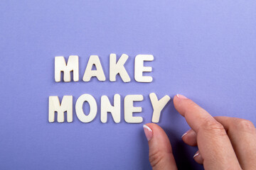 MAKE MONEY. White wooden letters on a purple background