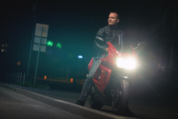Naklejka na ściany i meble A man on the motorbike at empty night city street.