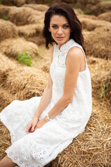 Beautiful woman wearing white dress on dry grass