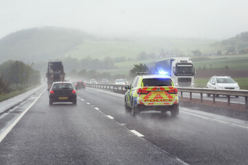 Fototapeta na wymiar Police siren flashing blue lights on motorway in bad weather conditions