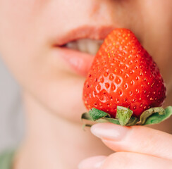 Close up beautiful young woman lifted Strawberries to her lips.