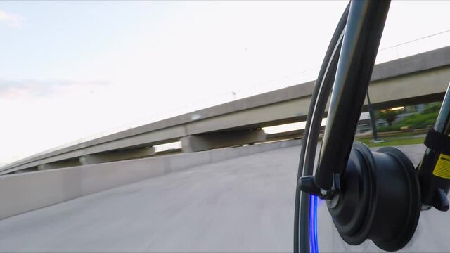 Ebike with blue lights moves fast on path under bridge, low pov shot
