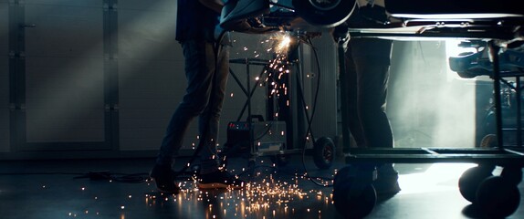 CU Sparks falling on the ground as mechanic welding a go kart car inside garage