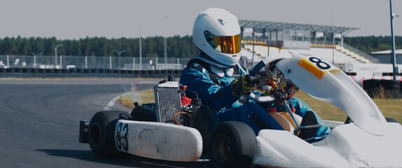 Front view of teenager professional racer driving his go kart on a race track. Shot with 2x anamorphic lens - obrazy, fototapety, plakaty