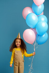 Fototapeta na wymiar Funny little girl in cap holds a bunch of balloons